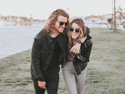 Pareja sonríe mientras dan un paseo frente a un lago