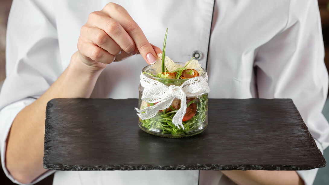 A chef presenting an enticing dish, showcasing current culinary trends