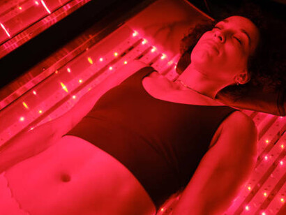 A woman receiving rejuvenating red light therapy on an LED bed, promoting healing and skin revitalization