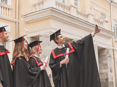 Young graduates capturing joyful moments with selfies on campus, celebrating their achievements at university