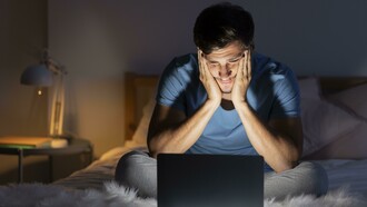 Late at night, a man stares at his computer screen, insomnia keeping him awake