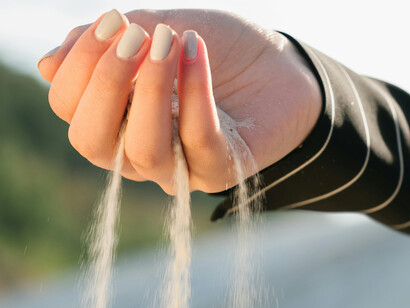 Sand slips through the fingers of a woman's hand