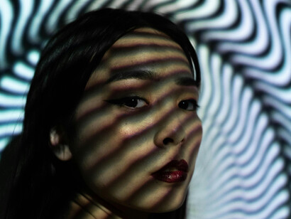 Close up of a young woman's face, with an hypnotic pattern cast on her