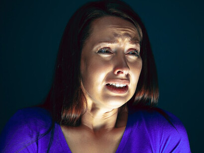 A woman looking at her screen with a scared and shocked expression