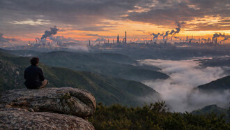 A solitary figure overlooks a mist-covered valley as industrial smoke rises on the horizon, capturing the tension between nature’s illusion of harmony and the persistent pressures shaping life