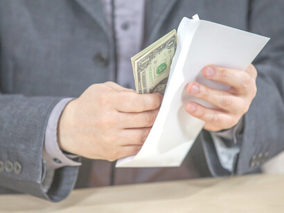A man in a suit covertly conceals cash, illustrating corruption