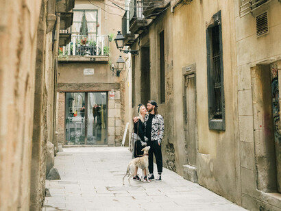 A man and a woman hugging while walking their dog in a Barcelona alley