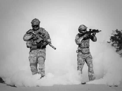 Amidst a barren landscape, two soldiers clad in tactical gear reflect the ongoing tensions in the international order, where global power battles manifest in conflict zones, reshaping alliances and igniting geopolitical rivalries