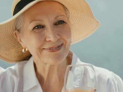 An eldery woman wearing a hat and holding a glass
