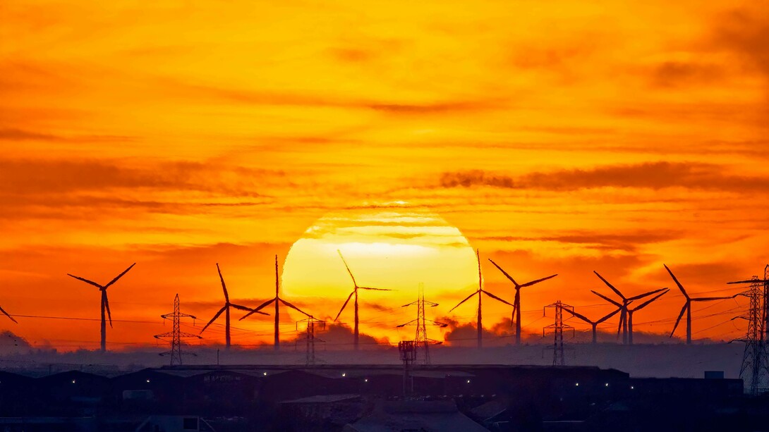 The sun setting in a field of energy-efficient windmills