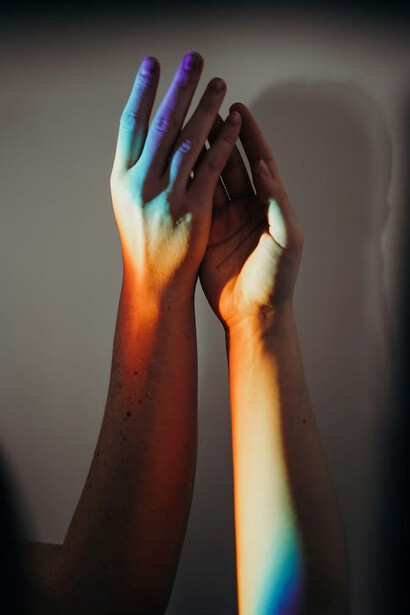 Hands of individuals adorned with rainbow colors