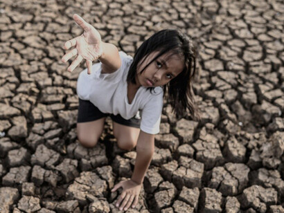 The girl sat apart, raising her hand to the sky, praying for rain to nourish the parched earth affected by global warming