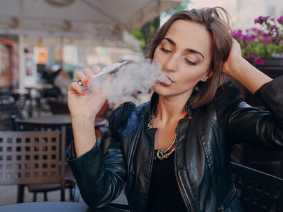 A woman taking a relaxing vape break outdoors