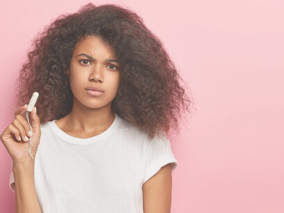 African American woman holding a sanitary pad, highlighting the challenges of menstrual product access and personal hygiene