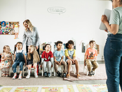 Two female teachers showing lessons to several young students sitting on chairs