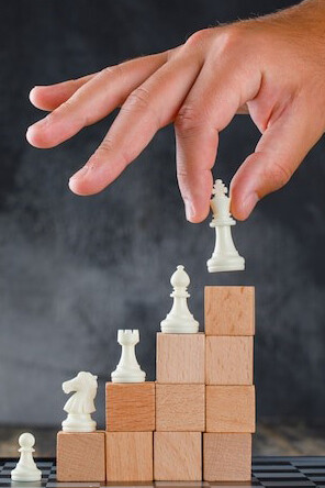 Business success concept: a man placing a chess piece on top of a pyramid of blocks, symbolizing strategic growth and decision-making