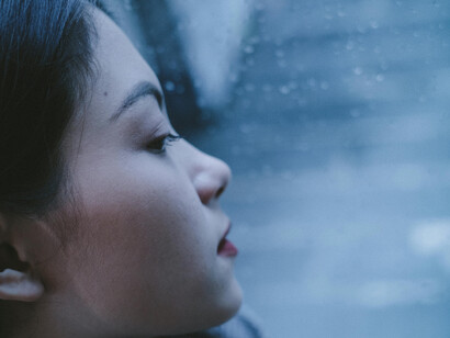 A close up of a young woman looking out the window, pensive