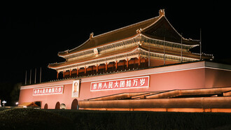 Night view of Tiananmen Gate in Beijing, where a large portrait of Mao Zedong hangs above its central arch