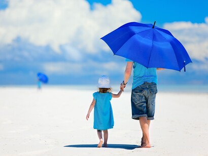 Un padre protege a su hija del sol en la playa