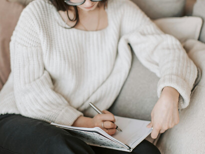 A woman sitting on a sofa, taking notes