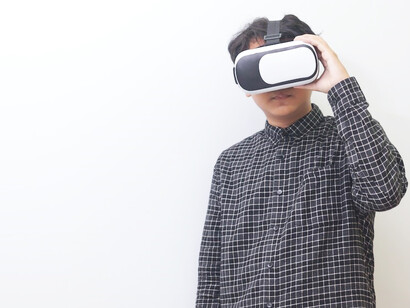 An Asian man delves into the realm of virtual reality, donning VR glasses and immersing himself in exciting gaming adventures