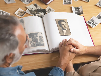 A pair of individuals shares a tender moment, flipping through a photo album that unfolds the stories of their ancestors and family history