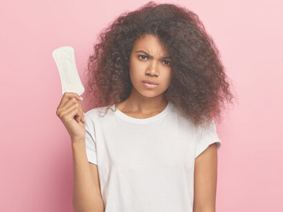 African American woman holding a sanitary pad, illustrating the struggle with menstrual product access and personal hygiene challenges