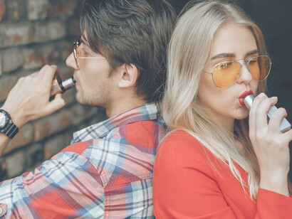 Young couple sharing a vape, using electronic cigarettes in unison