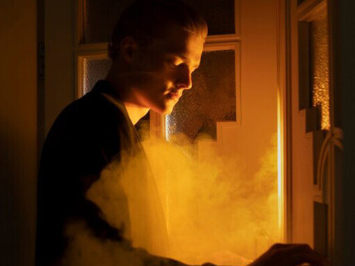 Side view of a man posing amidst smoke, evoking themes of loneliness and individualism, captured in a compelling image