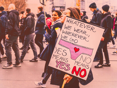A creative sign reading "whatever we wear, wherever we go, yes means yes, no means no" as a symbol of recapturing their currency of power