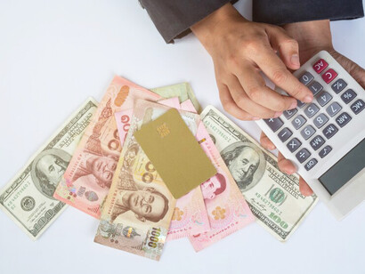 A businesswoman counting money and coins on her desk, symbolizing profit and capitalism
