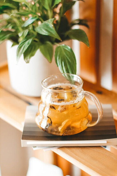 Glass pot with aromatic brewed herbal tea on shelf