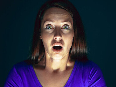 A woman with a distressed expression while viewing alarming news on the screen