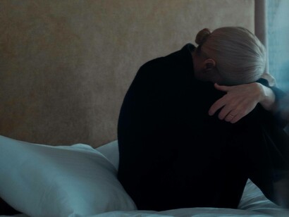 A woman depressed is crying with her head covered by her knees in bed