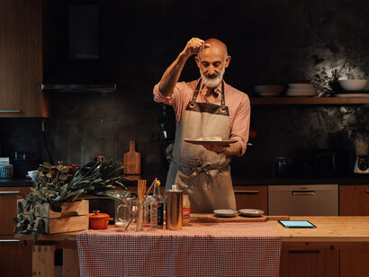 A middle-aged man giving a final seasoning to his dishes