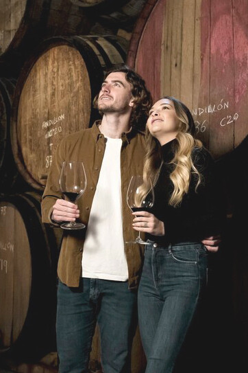 Young people wearing glasses are surrounded by oak barrels