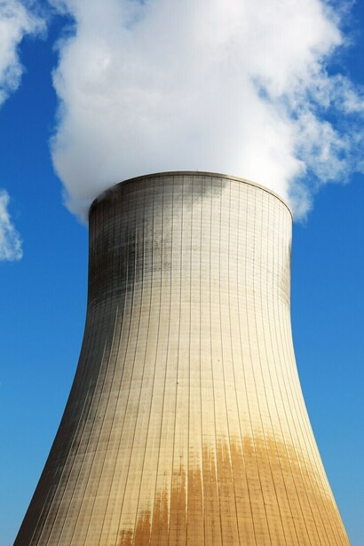 A summer view of a nuclear power plant's smokestacks, capturing the contrast between industry and nature