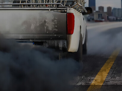 Spotlighting the city's air pollution crisis, this image features a diesel vehicle exhaust pipe emitting pollutants on a busy highway. It underscores the importance of environmental awareness and the pressing need for sustainable transportation solutions to address urban air quality challenges