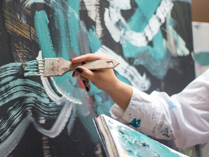 A female artist engrossed in her creative process, painting on a canvas