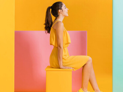Woman wearing a yellow dress posed against a vibrant, colorful background