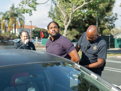 Man stares into the distance while being arrested