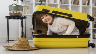 Smiling toddler sitting playfully inside an open suitcase