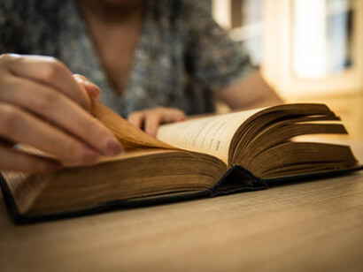 Woman's hand reading book on wooden table