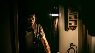 Man gazing into a mirror, gripping his face in confusion