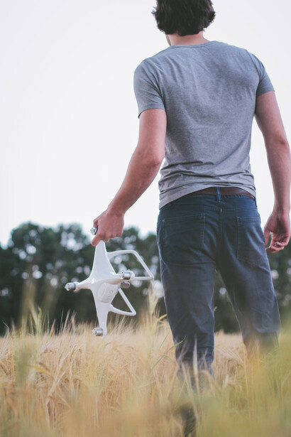 A man confidently grasps a sleek white and gray drone controller, ready to navigate and control the advanced aerial device with precision