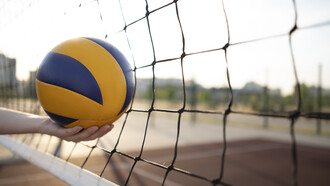 During a fast-paced rally, the ball strikes the net in a volleyball match, creating a moment of suspense as players prepare for the next move