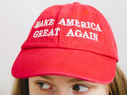 A woman wearing a hat with Trump's main political slogan