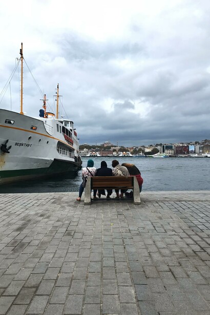 People sitting on a bench in a port in Istanbul, Turkey
