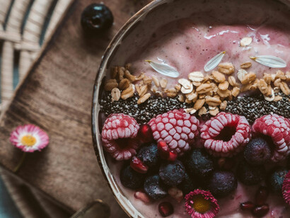 A healthy bowl of açaí yogurt with berries and granola on a wooden table
