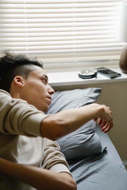 Man reaches for technology gadgets while in bed